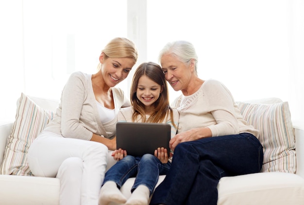 Familien-, Generations-, Technologie- und Personenkonzept - lächelnde Mutter, Tochter und Großmutter mit Tablet-PC-Computer, die zu Hause auf der Couch sitzen