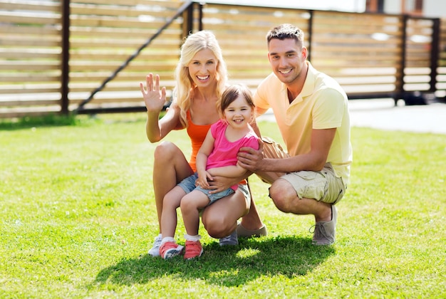 Familien-, Glücks-, Adoptions-, Gesten- und Personenkonzept - glückliche Familie winkt im Freien mit der Hand