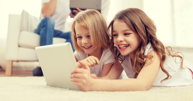 Foto familien-, kinder-, technologie- und wohnkonzept - lächelnde schwester mit tablet-pc-computer und eltern auf dem rücken mit laptop
