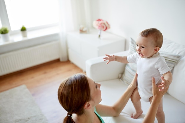 Familien-, Kinder- und Elternschaftskonzept - glücklich lächelnde junge Mutter mit kleinem Baby zu Hause