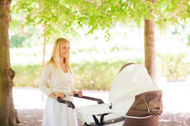 Familien-, Kinder- und Elternschaftskonzept - glückliche Mutter mit Kinderwagen im Park