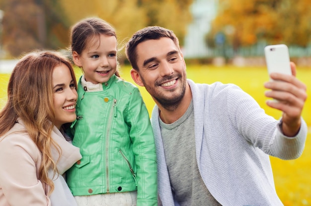 Familien-, Kindheits-, Saison-, Technologie- und Personenkonzept - glückliche Familie, die im Herbstpark ein Selfie mit dem Smartphone macht