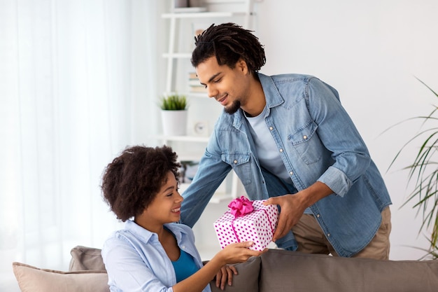 Familien-, Urlaubs- und Menschenkonzept - glückliches Paar mit Geschenkbox zu Hause