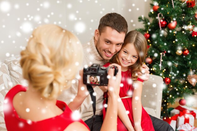 Familien-, Weihnachts-, Weihnachts-, Winter-, Glücks- und Menschenkonzept - Mutter, die ein Bild von lächelndem Vater und Tochter macht