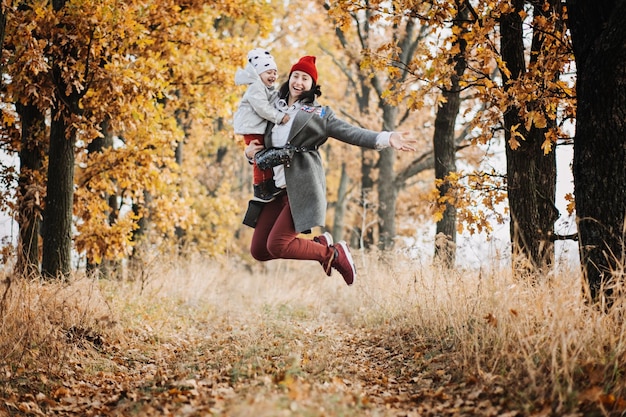 Familienaktivitäten im Herbst Glückliche Familie, alleinerziehende Mutter und Kleinkind, Mädchen, die draußen im Herbstpark spielen