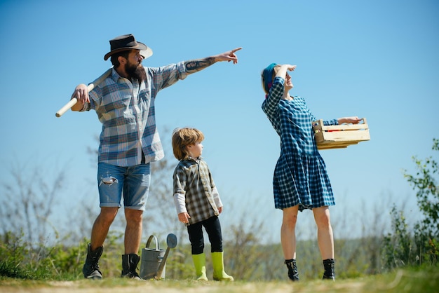 Familienbauern, die auf den Himmel zeigen, der sich im Frühling bei der Gartenarbeit zeigt, glückliche Familie, die erntet und Lo hat