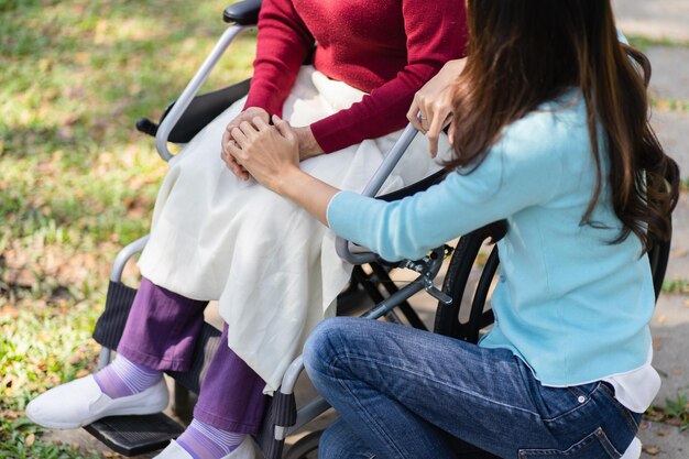 Foto familienbeziehung asiatische seniorin im rollstuhl mit glücklicher tochter, die eine pflegekraft an der hand hält, während sie zeit miteinander verbringen