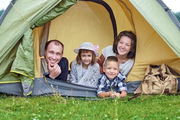 Familieneltern und zwei Kinder im Lagerzelt. Glückliche Mutter, Vater, Sohn und Tochter in den Sommerferien