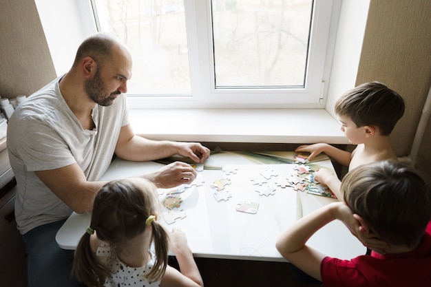 Foto familienfreizeit: vater, söhne und tochter spielen zusammen brettspiele