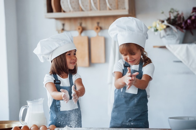 Familienkinder in weißer Kochuniform, die Essen in der Küche zubereiten.