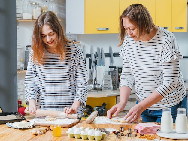 Familienkochhobby. Mutter und Tochter kochen zusammen und rollen Teig, um Lebkuchen zu machen.