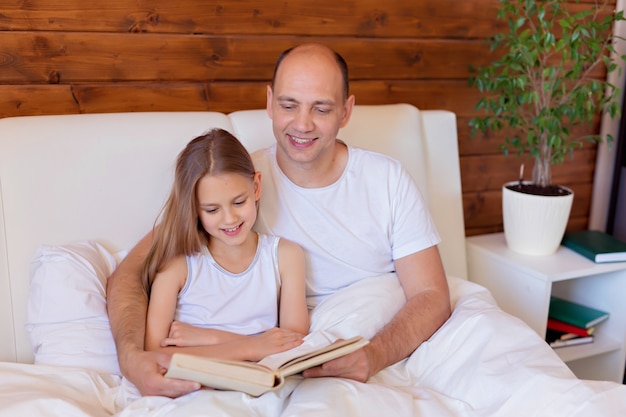 Familienlesung. Vater liest seiner Tochter vor dem Schlafengehen ein Buch vor