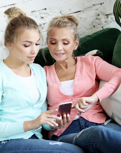 Foto familienmenschen und technologie alte frau und ihre erwachsene tochter mit smartphone zu hause