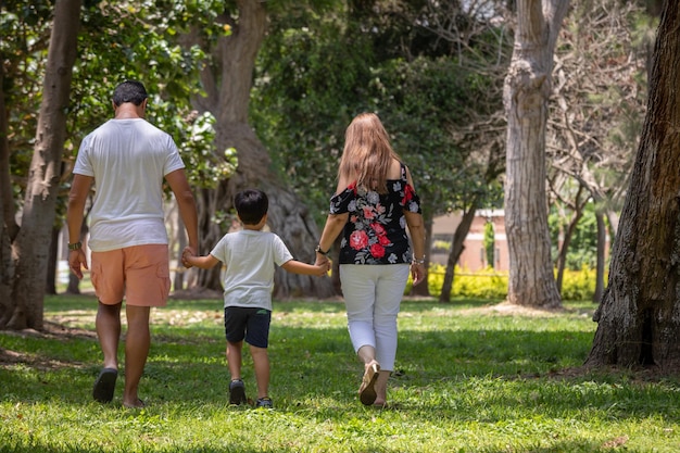 Familienmitglieder halten sich an den Händen und gehen zusammen in einem Park rückwärts