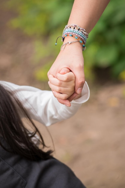 Familienmitglieder halten sich an den Händen, während sie durch den Park spazieren und eine glückliche Zeit mit der Familie verbringen