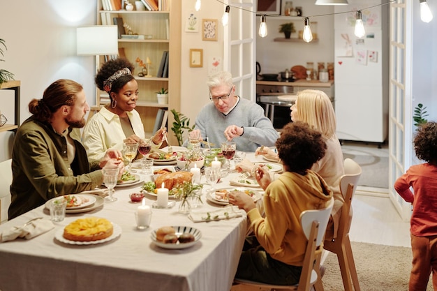 Familienmitglieder kommunizieren am servierten Tisch, während sie hausgemachtes Essen essen