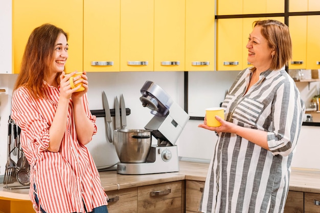 Familienmorgen Mutter und Tochter trinken Kaffee und unterhalten sich in der modernen Küche zu Hause