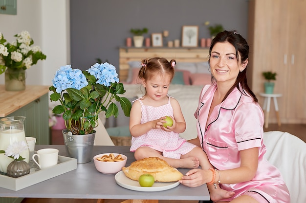 Familienmutter und kleine Tochter frühstücken morgens in der Küche
