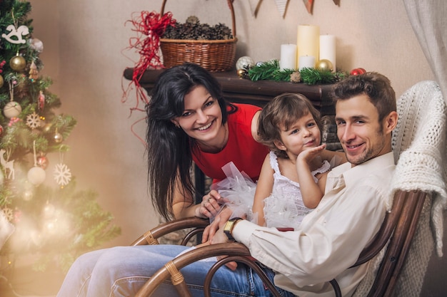 Familienmutter, Vater und Kinder mit Geschenken in schönen Kisten im Weihnachtsinterieur