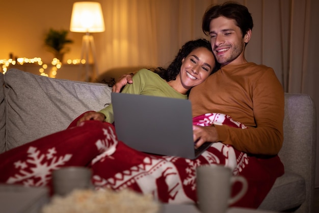 Familienpaar schaut sich zu Hause einen Weihnachtsfilm online auf dem Laptop an