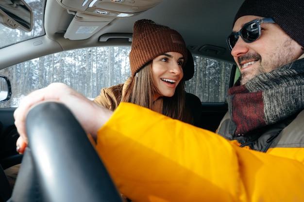 Familienpaar sitzt im Auto in Winterkleidung im Schneewald