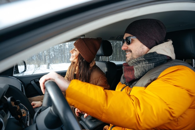 Familienpaar sitzt im Auto in Winterkleidung im Schneewald