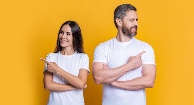 Familienpaar zeigt mit dem Finger Millennial Mann und Frau machen Angebot Angebot von Millennial Paar Freund und Freundin zeigen mit dem Finger Paar von Mann Frau isoliert auf gelb Angebot Werbung