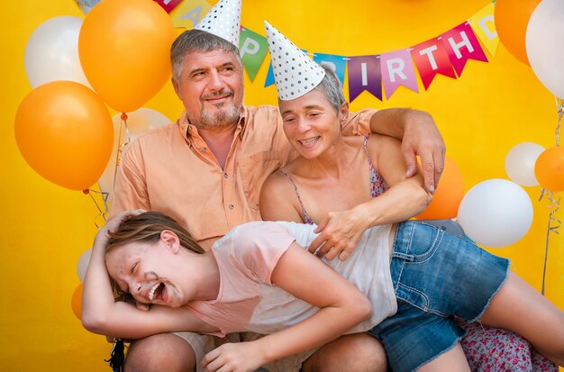 Familienporträt auf gelbem Grund. Das Mädchen legte sich auf die Knie ihrer Eltern