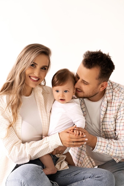 Familienporträt auf weißem Hintergrund, glückliches Familienkonzeptporträt. Die Eltern spielen mit dem Kind