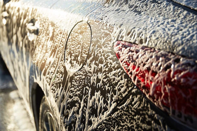 Familienreinigungsauto in Selbstbedienung bei Autowäsche bei Sonnenuntergang Auto mit weißem Schaum bedeckt Konzept der einfachen und unterhaltsamen Selbstbedienung
