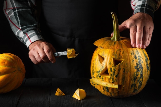 Familienspaß-Aktivität - geschnitzter Kürbis in Jack-o-Laterne für Halloween aus nächster Nähe. Mann mit Messer