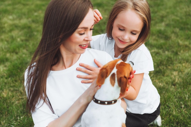 Familienspaziergang im Herbstpark Unterhaltung im Freien Mutter und Tochter gehen an einem sonnigen warmen Herbsttag mit dem Hund spazieren Ein Kind spielt mit einem Jack Russell Terrier im Park