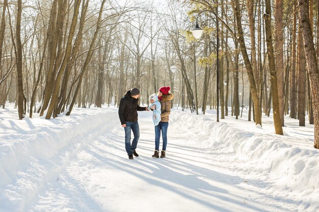 Familienspaziergang in einem Winterpark. Baby und Mutter und Vater