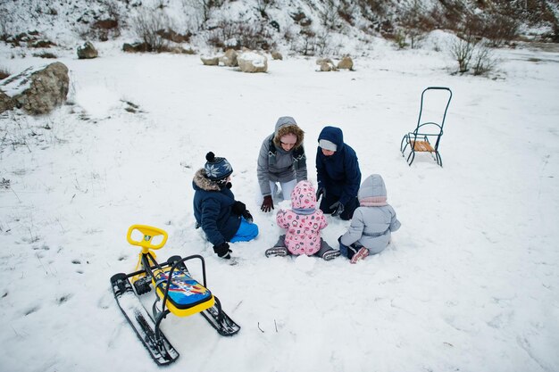 Familienspiele und Schlittenfahrten im Winter im Freien, Mutter und Kinder haben Spaß.