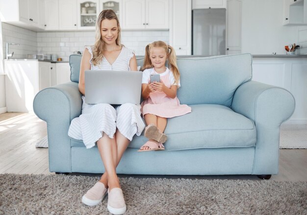 Familientelefon und Laptop mit einem Mädchen und einer Mutter auf dem Sofa in einem Wohnzimmer zu Hause zusammen während der Arbeit oder in sozialen Medien Computer-E-Mail und Kommunikation mit einer Frau und Tochter in einem Haus