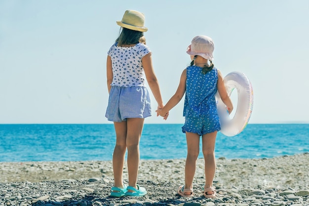 familienurlaub am meer, kinder gehen in strandklamotten ins wasser schwimmen