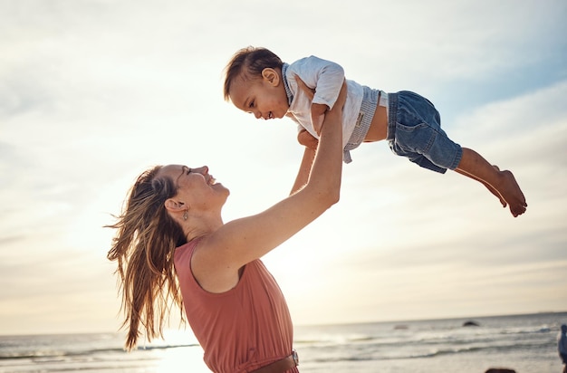 Familienurlaub am Strand und bei Sonnenuntergang mit Mutter und Heben des Kindes in der Luft für Spaß, Liebe und Fürsorge mit Unterstützung Frau und Baby freuen sich über die Bindungserfahrung während des Urlaubs auf Bali für Sommerreisen