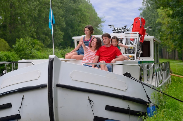 Familienurlaub, Reise auf einem Lastkahnboot im Kanal, glückliche Eltern mit Kindern, die Spaß auf Flusskreuzfahrt im Hausboot haben