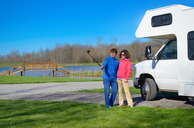 Familienurlaub, RV-Reise, glückliches Paar, das selfie vor Camper auf Urlaubsreise im Wohnmobil macht