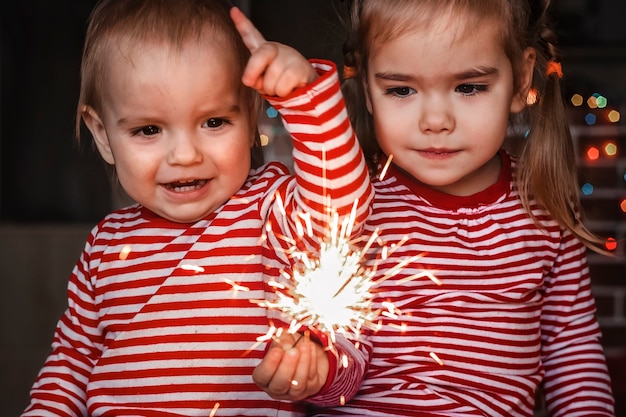 Familienurlaub zu Hause. Zwei glückliche Kinder, Kleinkindjunge und niedliches kleines Mädchen, das brennende Wunderkerze hält