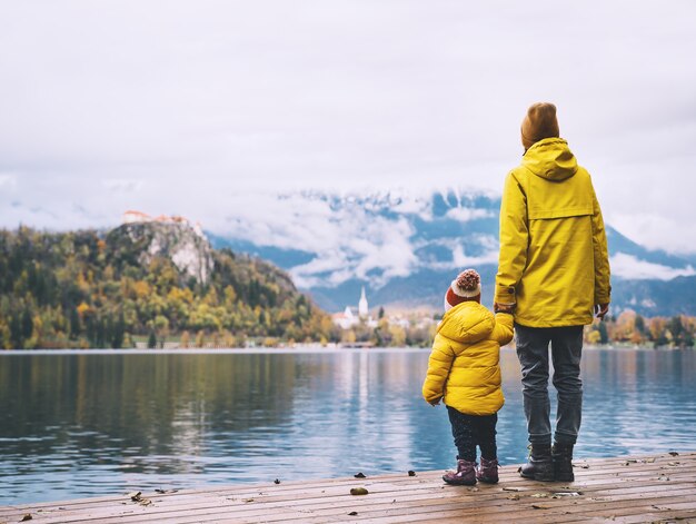 Family Travel Europe Mutter und Kind in gelben Regenmänteln mit Blick auf den Bleder See Slowenien