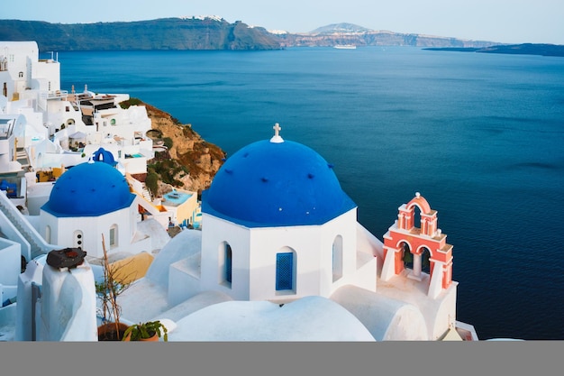 Famosa vista desde el mirador del pueblo de santorini oia con cúpula azul de la iglesia cristiana ortodoxa griega