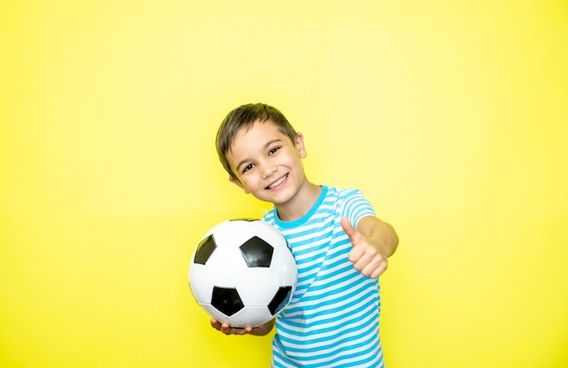 Fan-Sport-Junge-Spieler halten Fußball im gestreiften T-Shirt, das glücklich lächelnde Lachen-Show-Daumen feiert