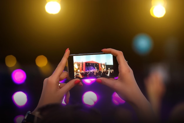 Foto fan tomando foto con celular en un concierto