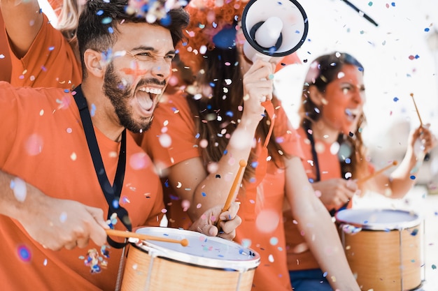 Los fanáticos del deporte naranja gritan mientras apoyan a su equipo fuera del estadio - Los fanáticos del fútbol se divierten en el evento de la competencia - Enfoque en la cara del hombre