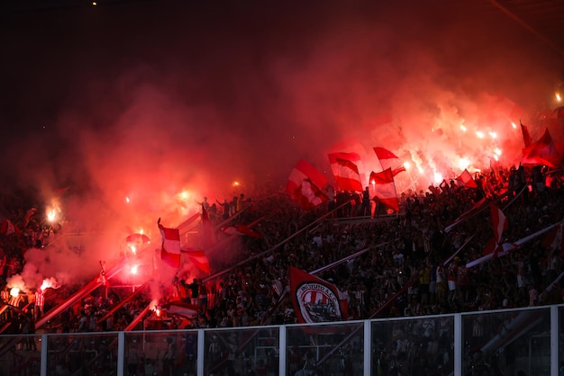 Los fanáticos del fútbol argentino encienden bengalas rojas en las gradas de un estadio