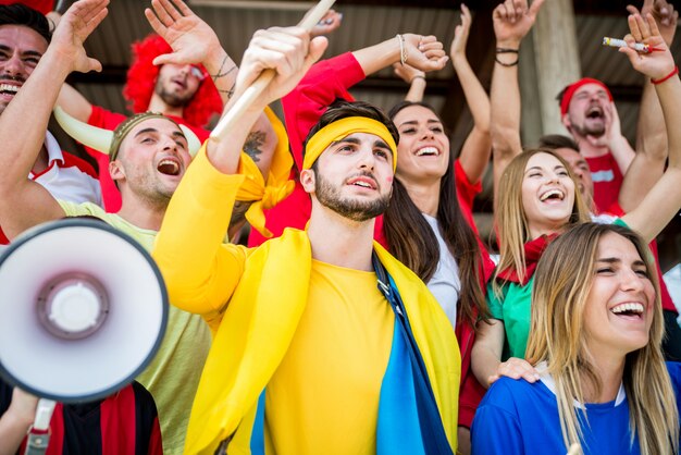 Fanáticos del fútbol en el estadio: fanáticos del fútbol que se divierten y miran un partido de fútbol