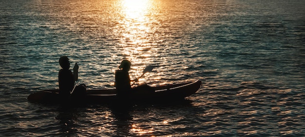 Fangen Sie einen romantischen Moment mit Liebe von der Silhouette eines Paares auf einem Boot mit Sonnenuntergang ein