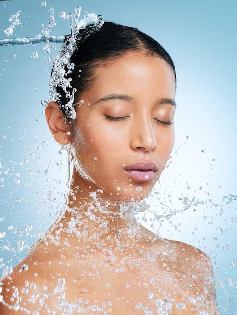 Fangen Sie mit jedem Duschen neu an Aufnahme einer attraktiven jungen Frau, die vor blauem Hintergrund im Studio posiert, während sie mit Wasser bespritzt wird