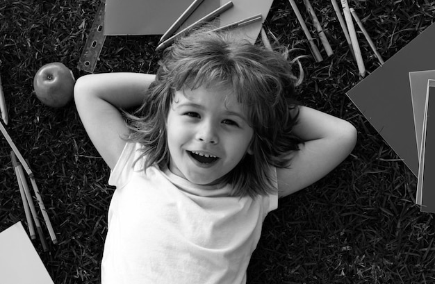 Fanny sorrindo cara de bonito menino de escola inteligente deitar-se na grama aluno feliz